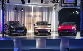 Drei Fahrzeuge der Marke Lynk & Co stehen auf einer Bühne im Scheinwerferlicht.