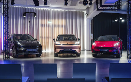 Drei Fahrzeuge der Marke Lynk & Co stehen auf einer Bühne im Scheinwerferlicht.