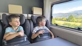 Zwillinge sitzen in ihren Kindersitzen nebeneinander.