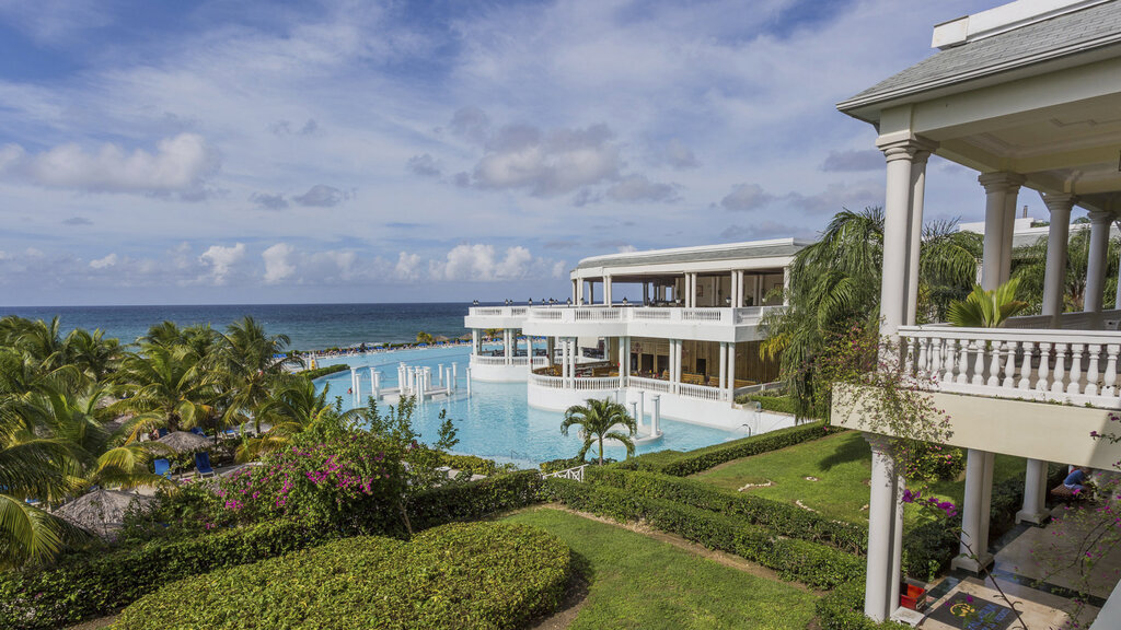 Gepflegte Resortanlage mit Pool und Meer im Hintergrund.