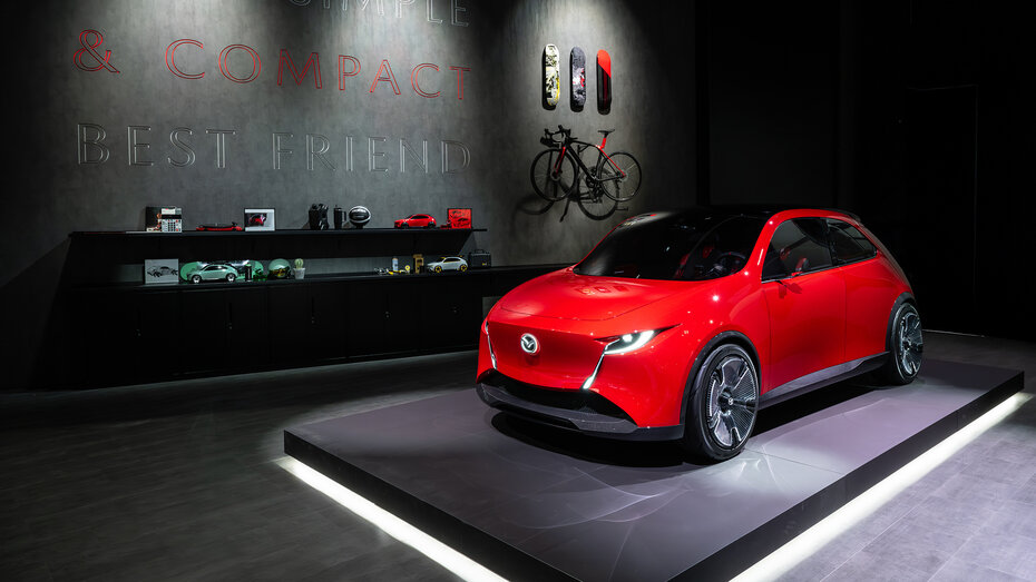 Ein roter Kleinwagen von Mazda auf einem Messestand