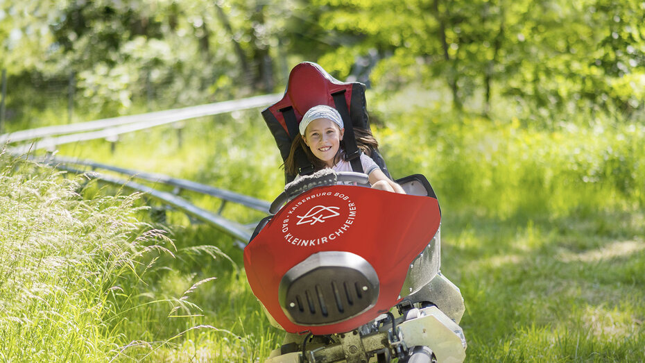Ein Kind rodelt auf der Sommerrodelbahn hinunter.