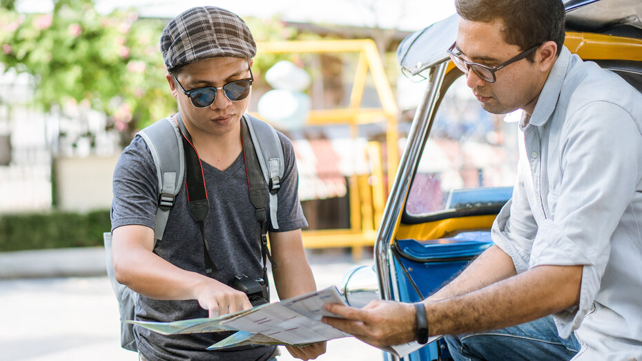 Traveller asking directions from taxi driver to get him to landmark in bangkok thailand.