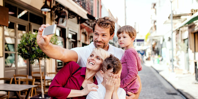 Eine Familie mit 2 Kindern macht gerade ein Selfie in einer Gasse.