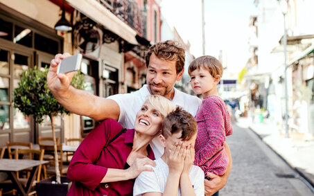 Eine Familie mit 2 Kindern macht gerade ein Selfie in einer Gasse.