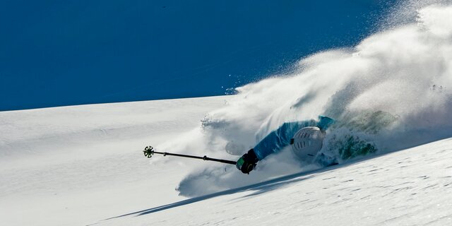 Skifahrer stürzt bei der Abfahrt auf einem verschneiten Berghang.