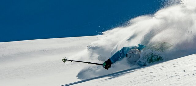 Skifahrer stürzt bei der Abfahrt auf einem verschneiten Berghang.