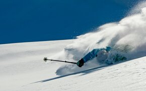 Skifahrer stürzt bei der Abfahrt auf einem verschneiten Berghang.