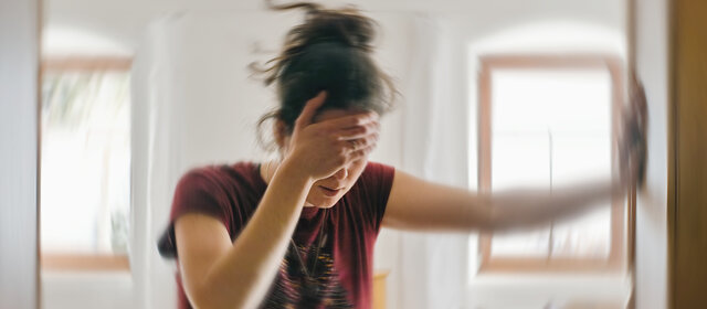 Verschwommenes Foto einer Frau, die unter Schwindel oder Benommenheit leidet, ausgelöst durch eine Erkrankung des Gehirns oder des Innenohrs.