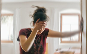 Verschwommenes Foto einer Frau, die unter Schwindel oder Benommenheit leidet, ausgelöst durch eine Erkrankung des Gehirns oder des Innenohrs.