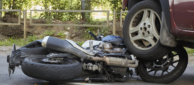 Ein Motorrad liegt unter dem Reifen eines Autos