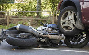 Ein Motorrad liegt unter dem Reifen eines Autos