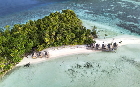 Luftaufnahme von Kri Island, Raja Ampat, Indonesien mit tropischem Strand, Meer und Überwasser-Bungalows