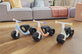 Imagebild des neuen Woom Wow Laufrads in 3 Farben, im Hintergrund eine Couch.