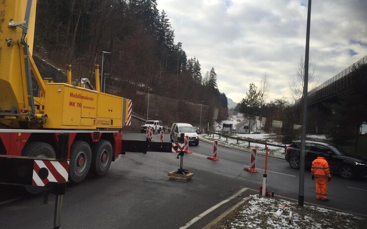 Baustellenfahrzeug und ein Bauarbeiter auf der Straße vor der Absperrung des Kreisverkehrs Innsbruck Mitte