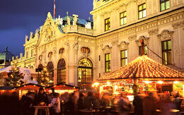 In der Abenddämmerung ein hell beleuchteter Weihnachtsmarkt vor einem schönen, großen, alten Schloss.