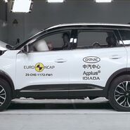 Das Foto zeigt ein weißes Auto von der Seite, das gerade im Zuge eines Crashtests frontal gegen ein Hindernis prallt.