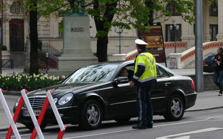demo_polizei.jpg Polizist der ein Auto vor einem gesperrten Straßenabschnitt anhält.