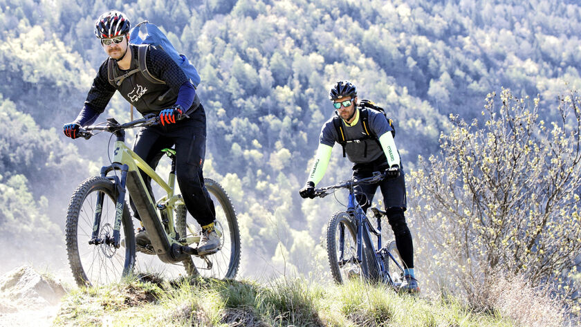 2 Radfahrer auf E-Mountain-Bikes unterwegs auf einem Berg.