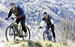 2 Radfahrer auf E-Mountain-Bikes unterwegs auf einem Berg.