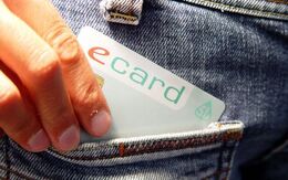Eine Hand die gerade eine e-Card in eine Jeanshosentasche steckt.