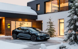 Ein Elektroauto steht vor einem Haus geparkt in verschneiter Umgebung.