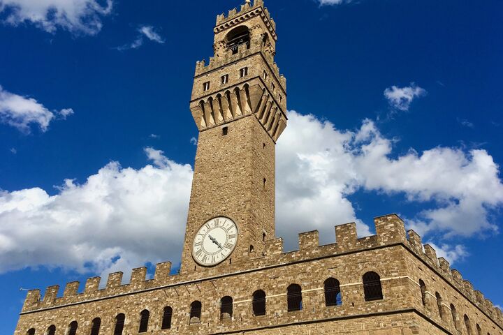Ein Steingebäude mit einem hohen Turm mit einer Uhr