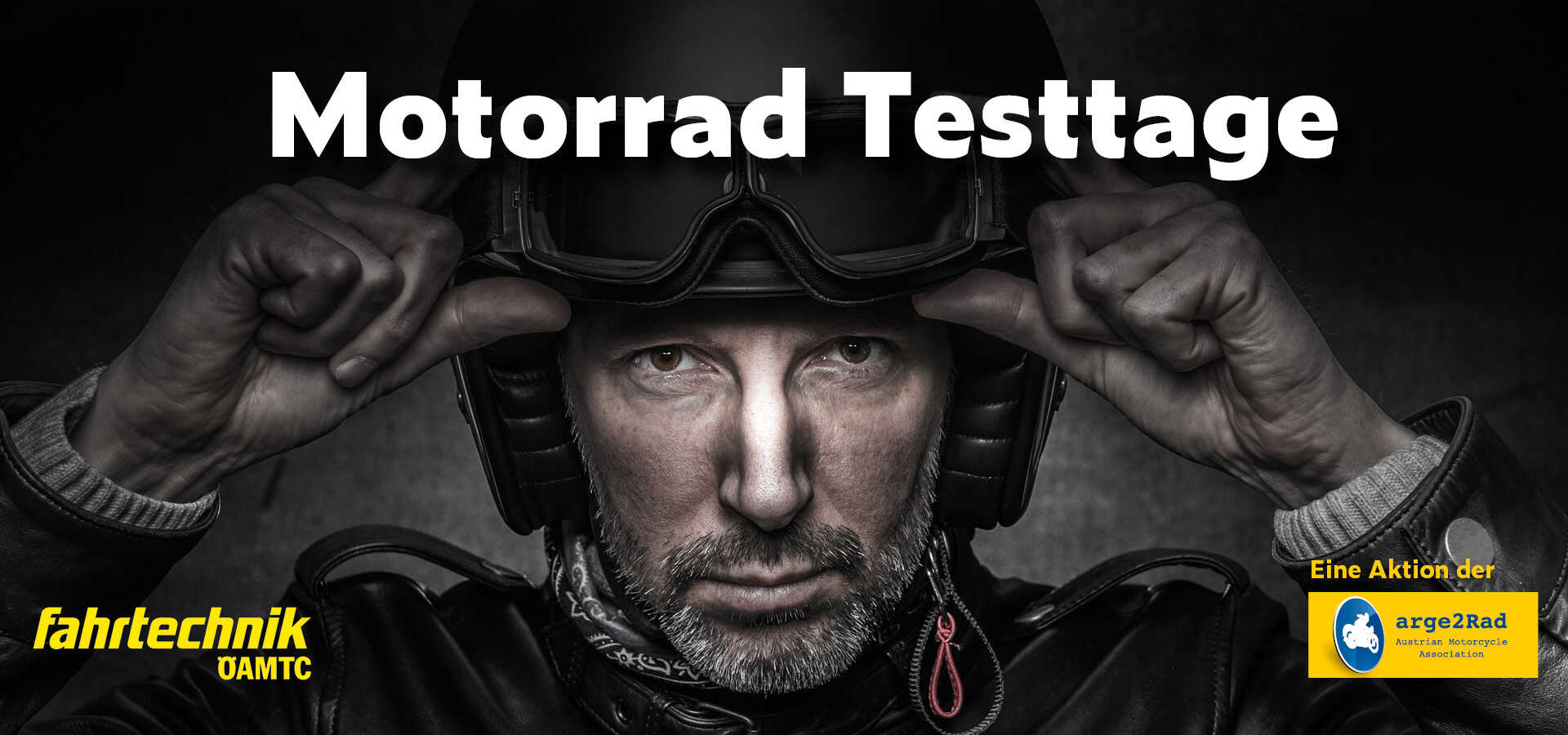 Ein Mann mit Motorradhelm zieht mit beiden Händen seine Motorradbrille nach unten. Er trägt eine Lederjacke und ein Halstuch.