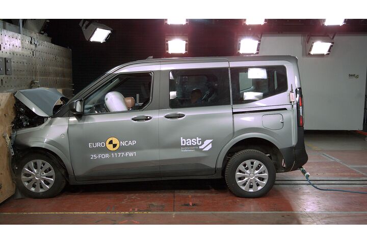 Das Foto zeigt ein graues Auto von der Seite, das gerade im Zuge eines Crashtests frontal gegen ein Hindernis prallt.