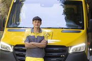 Auf dem Bild sieht man einen jungen ÖAMTC Mitarbeiter. er lehnt mit verschränkten Armen an einen gelben Klein LKW.