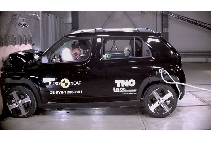 Das Foto zeigt ein schwarzes Auto von der Seite, das gerade im Zuge eines Crashtests frontal gegen ein Hindernis prallt.