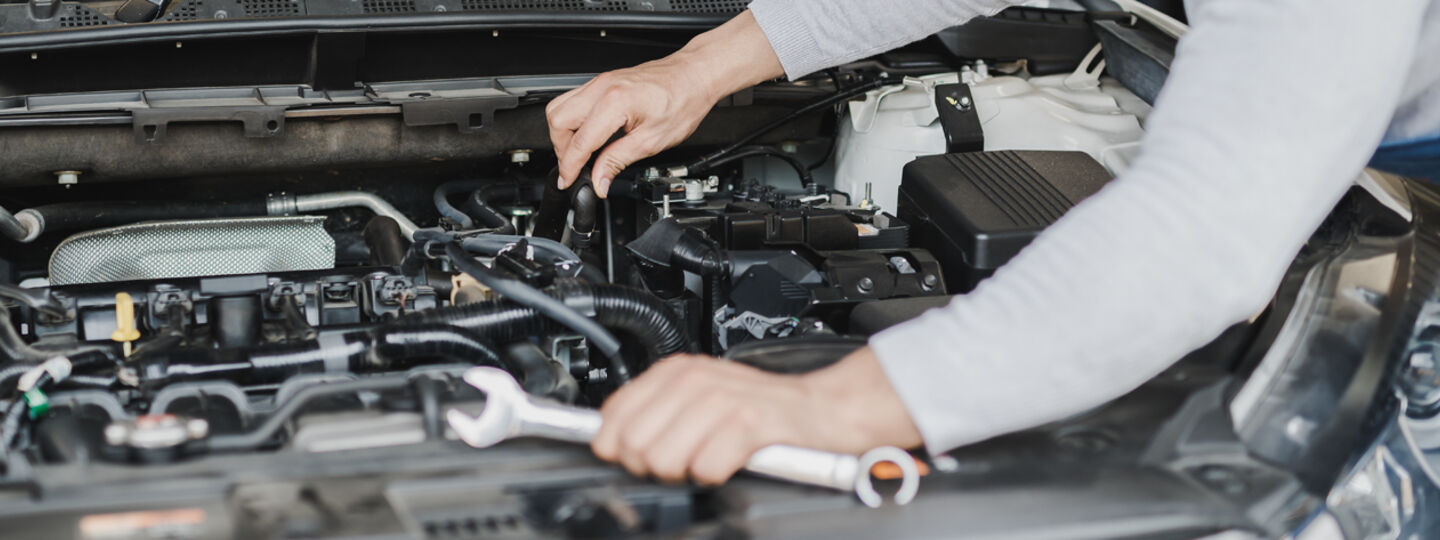 Kfz-Techniker begutachtet das Innere unter der Motorhaube eines Autos.