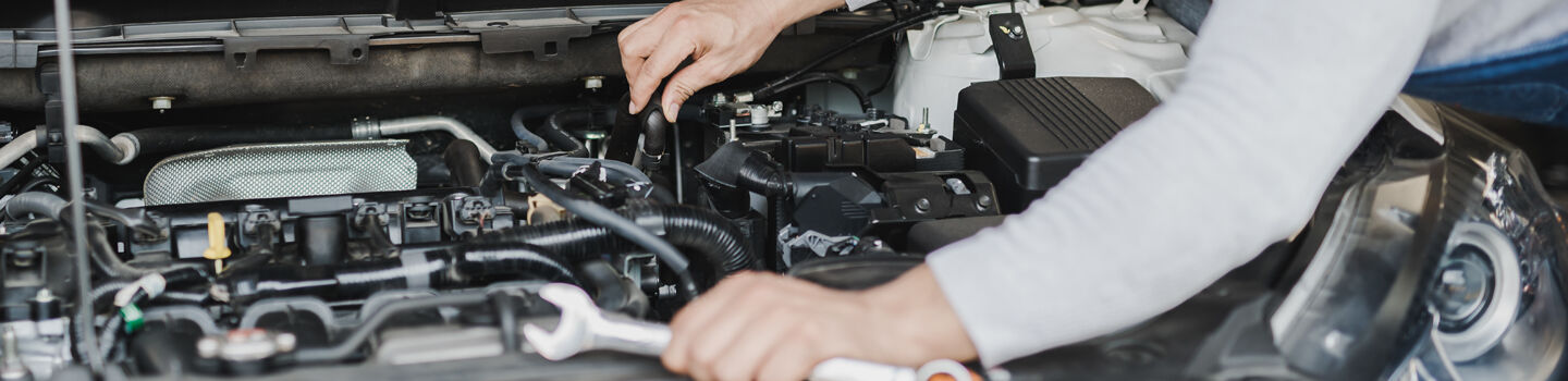 Kfz-Techniker begutachtet das Innere unter der Motorhaube eines Autos.