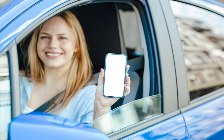 Digitaler Führerschein Junge Frau zeigt ihr Handy durch das Fenster des Autos.