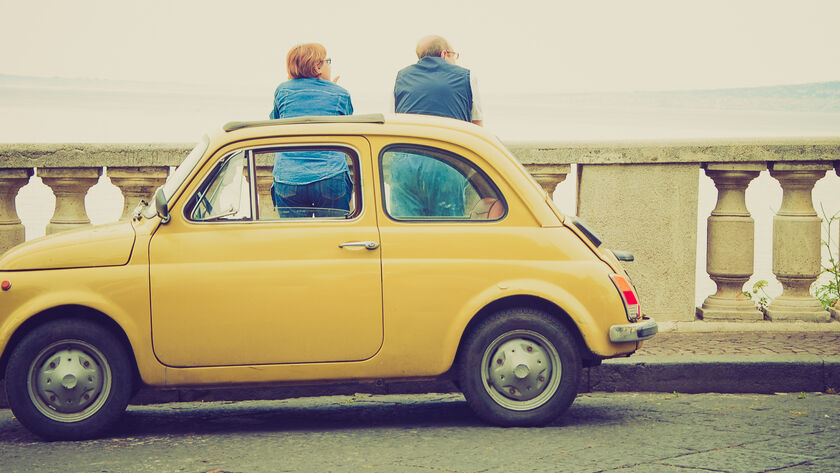 Ein Fiat 500 Oldtimer steht auf einer Brücke, während zwei Personen die Aussicht genießen.