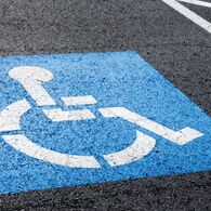 Behindertenparkplatz Behindertenparkplatz mit einem blau/weißen Rollstuhlpiktogramm auf Straßenasphalt.