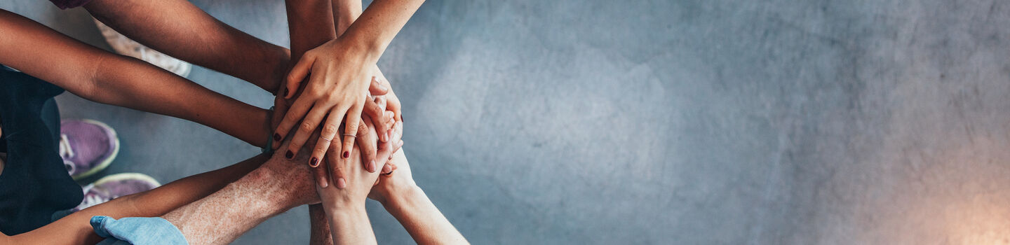 Eine Gruppe von Personen steht zusammen und hält sich an den Händen.