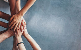 Eine Gruppe von Personen steht zusammen und hält sich an den Händen.