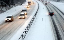 Autos fahren auf einer verschneiten Autobahn, die von Schnee bedeckt ist, bei winterlichen Bedingungen.