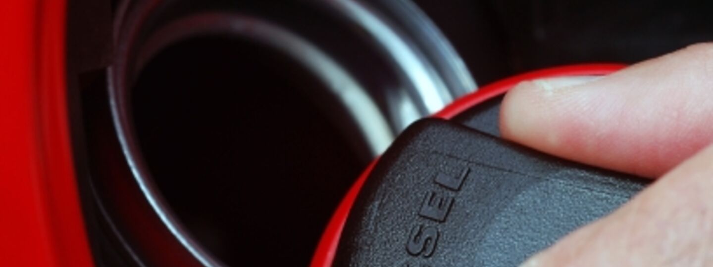 Ein Tankdeckel von einem Dieselfahrzeug wird ein einer Hand geöffnet.