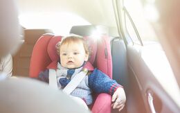 Baby mit Weste, scheint etwas energielos, im Autositz, die Sonne scheint ins Auto.