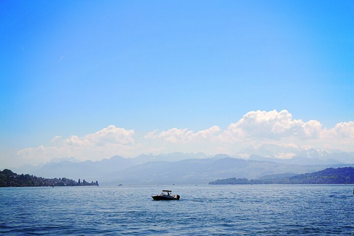 Ein kleines Boot, das bei blauem Himmel auf dem Zürichsee fährt