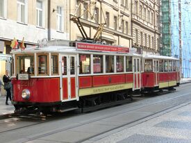 zwei rote historische Straßenbahnwaggons in einer Straße in Prag