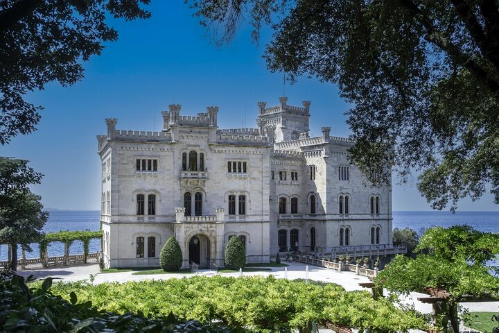 Eine weiße Burg umgeben von einer Gartenanlage direkt am Meer
