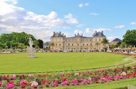 Ein Schloss im Jardin du Luxembourg mit einer Wiese im Vordergrund