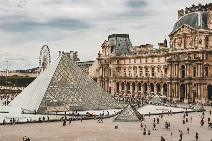 Blick auf einen großen Platz mit der Louvre-Pyramide in Paris