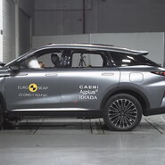 Das Foto zeigt ein graues Auto von der Seite, das gerade im Zuge eines Crashtests frontal gegen ein Hindernis prallt.