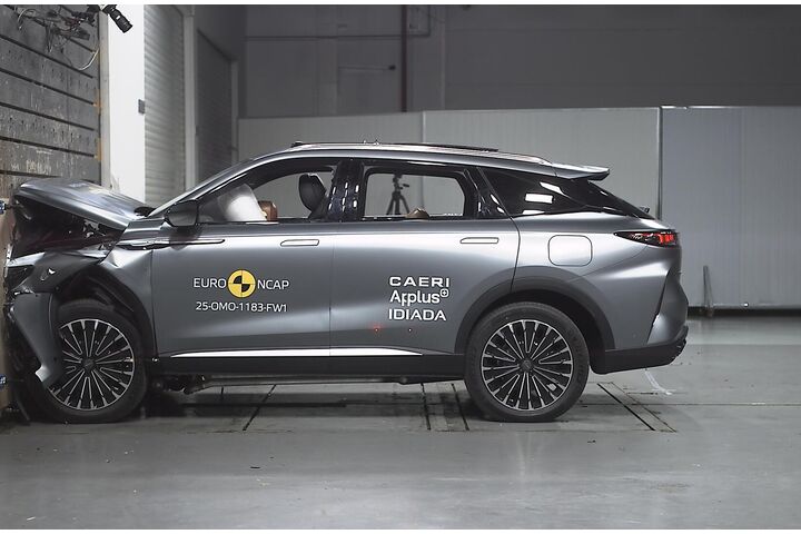 Das Foto zeigt ein graues Auto von der Seite, das gerade im Zuge eines Crashtests frontal gegen ein Hindernis prallt.