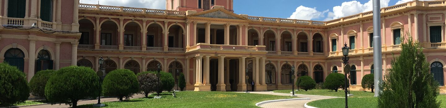 Die imposante Fassade des Palacio de los López in Paraguay verzaubert mit ihrem charakteristischen honigfarbenen Sandstein, verstärkt durch kraftvolle Säulen und elegante Balkone.