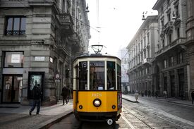 eine gelbe Straßenbahn fährt in einer Straße in Mailand